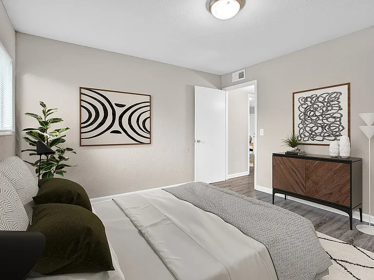 Inviting modern bedroom with contemporary decor, featuring elegant hardwood floors and artistic wall hangings.