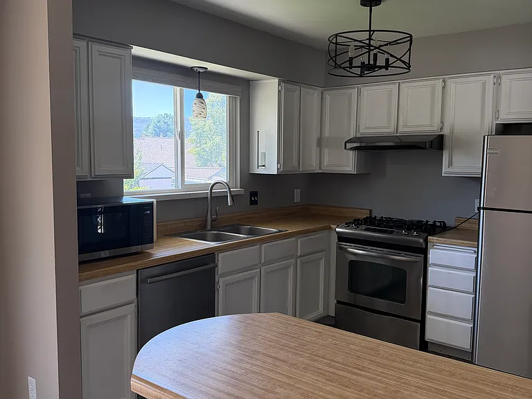 Upstairs kitchen with microwave, dishwasher, range stove, & refrigerator. New paint.