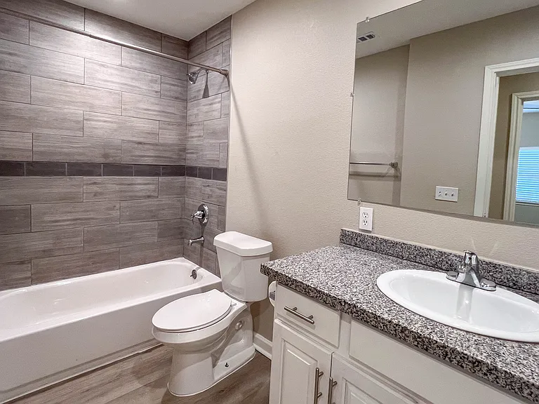 Updated second full bath with granite countertop, white cabinetry, and tiled tub/shower surround.