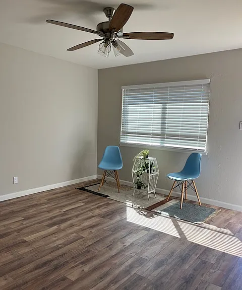 Enter the unit into the living space with large window for ample natural light, wood laminate flooring, two tone paint, ceiling fan, faux wood blinds.