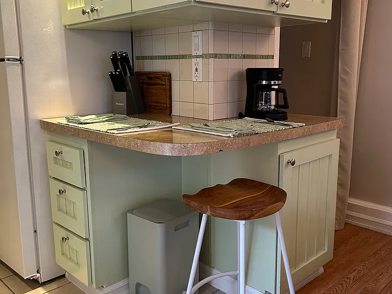 Corner bar with stool. Small coffee pot, rice cooker, vegetable chopper and knife set included in furnishings.