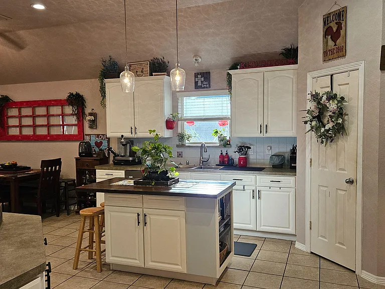 Functional kitchen with ample white cabinetry, center island seating, and adjacent dining area for everyday meals.