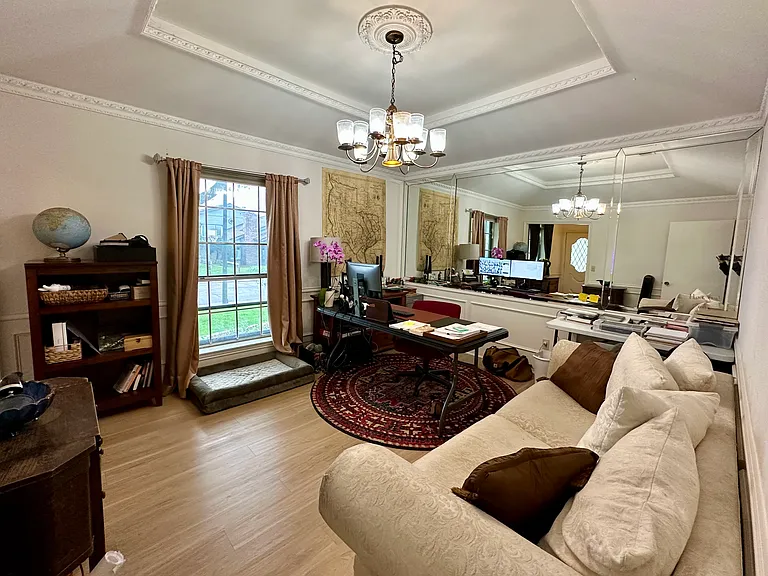 Front formal dining area featuring ornamental molding, light wood-style flooring, a tray ceiling, and a notable chandelier. Can be used as an office.