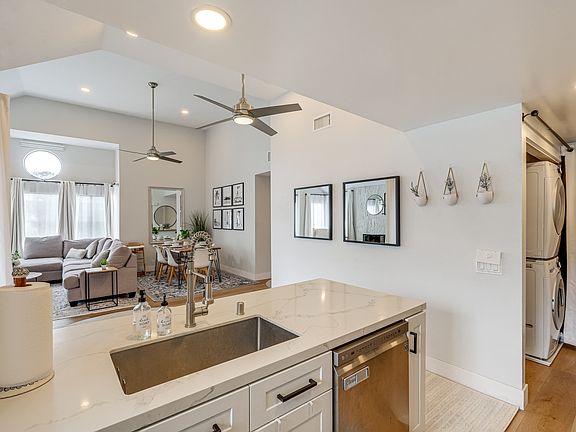 View of dining and living room from kitchen. Stacked washer and dryer visible on right.