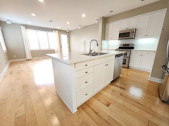 The brightly-lit kitchen, dining room, and living room