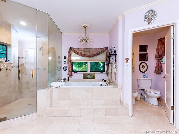 Marble master bath with his and her sink, bidet and an abundance of windows.