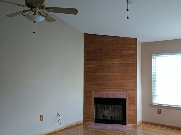 Living room with 2 ceiling fans and a wood burning fireplace