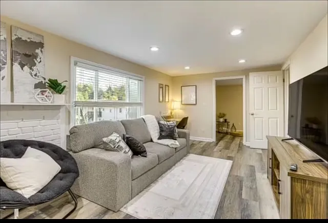 Bright living room with comfy sofa, cozy papasan chair, large falt screen TV, and a dedicated wrok space -- perfect for relaxing or workign from home.