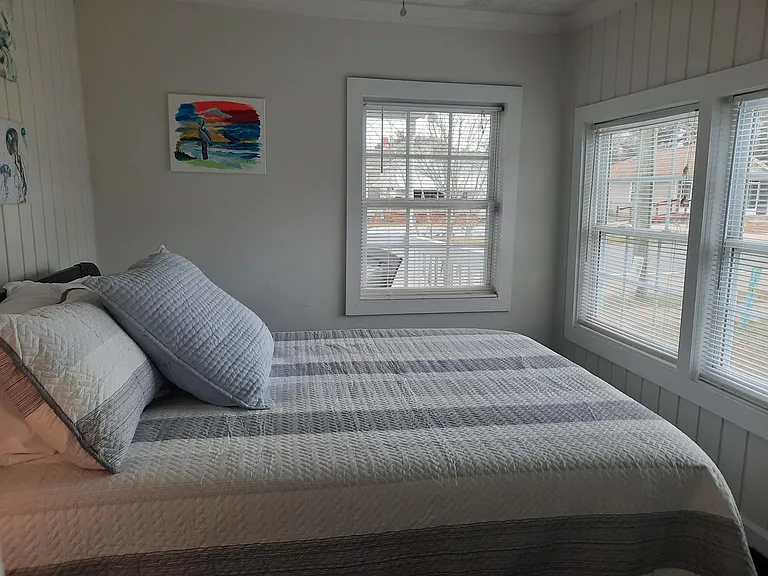 Bright bedroom with a clear view of the street and large Google TV on the wall. Touch lamps with plugs for USB and electric. Queen bed.
