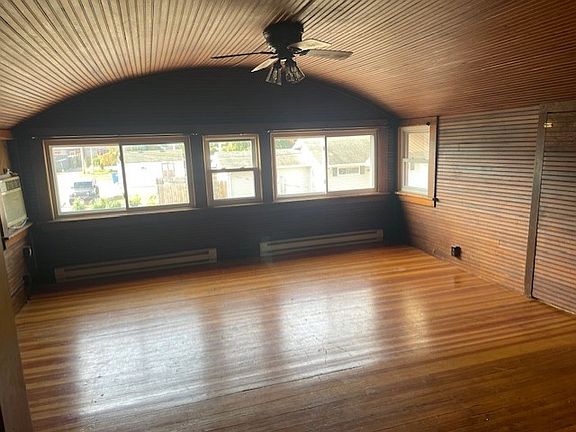 Living room with stunning wood lap on ceiling and walls and wooden floors. With curtain rods ready for curtains.
