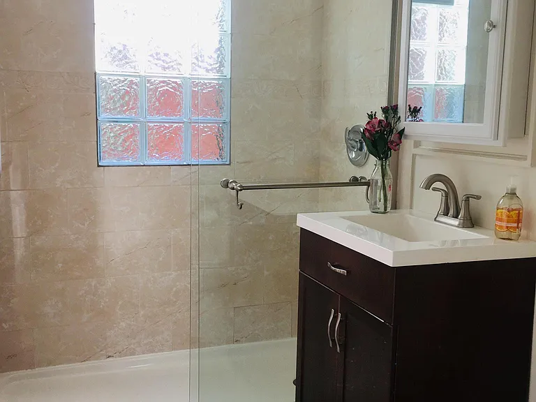 Newly renovated bathroom with new sink, toilet, shower and tile flooring.