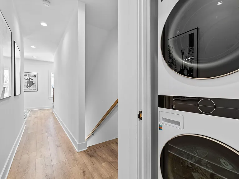 Convenient hallway with recessed lighting, wood-look floors, and an in-unit stacked washer/dryer tucked into a closet.
