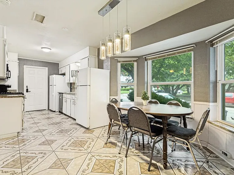 Eat-in kitchen with a dining table, ample cabinet storage, and large windows overlooking the yard.