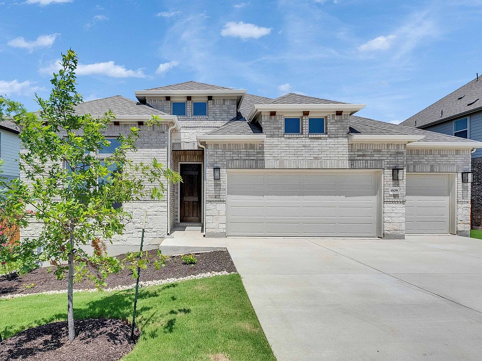 Elegant stone facade with expansive three-car garage and pristine landscaping in Retreat at San Gabr