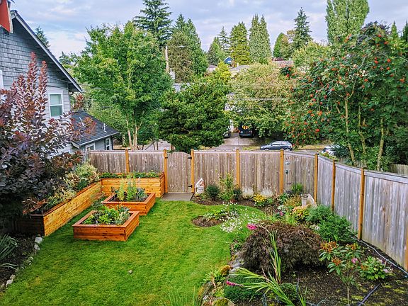 Lush, fully-fenced front yard with lots of greenery and privacy. Veggie boxes are yours for the planting!