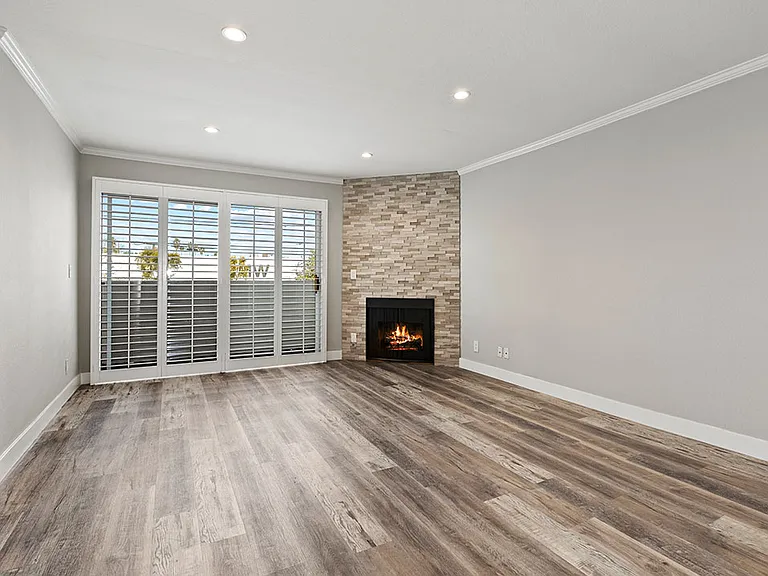Hardwood floored living room with stone accented fireplace.
