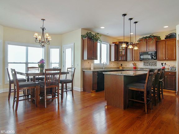 Spacious eating area with gleaming hardwood floors, custom back splash and staggered cabinets.