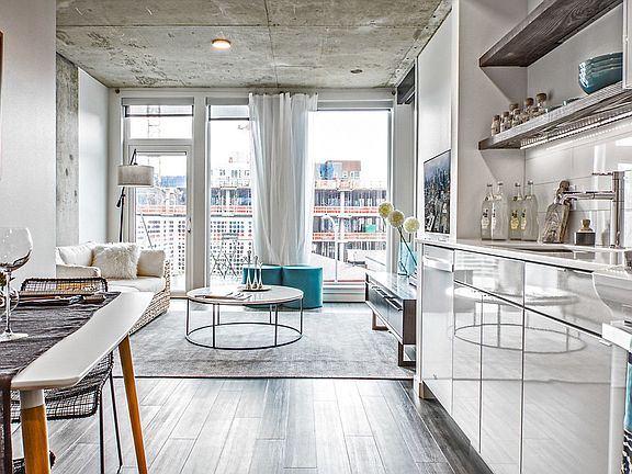 Open concept, staged apartment with hardwood style flooring and floor to ceiling windows.