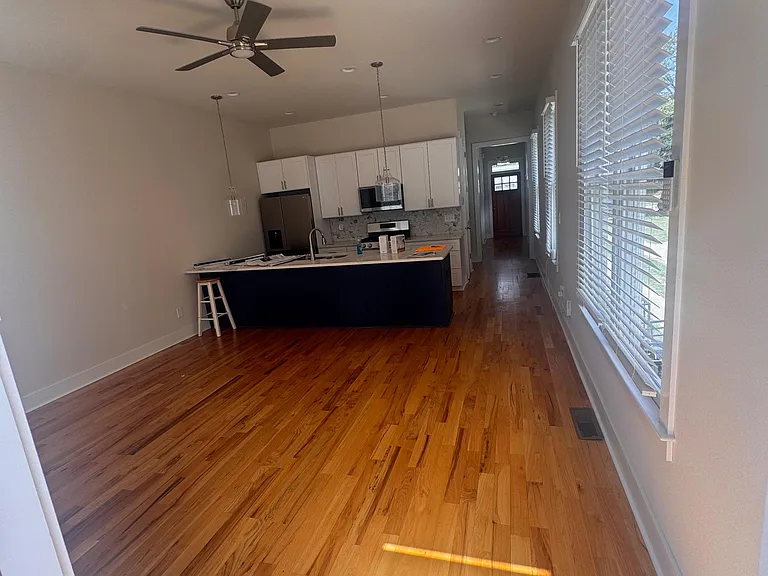 Open-concept kitchen with a large island, white cabinetry, stainless appliances, and wide-plank hardwood flooring.