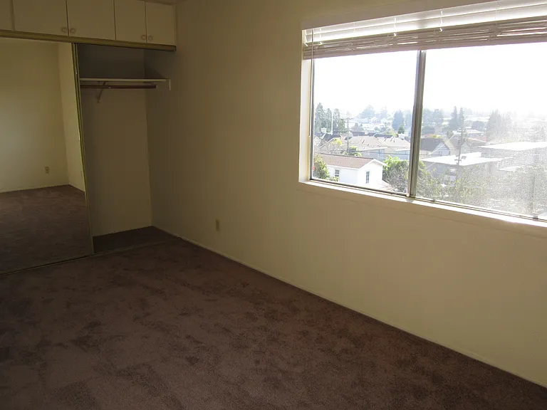 Second/middle bedroom with natural light window, mirrored sliding doors with upper cabinet area