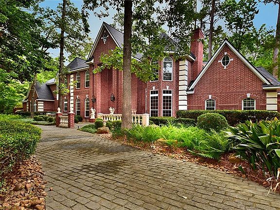 The patterned concrete circle drive winds through the tall mature trees in this beautiful setting.