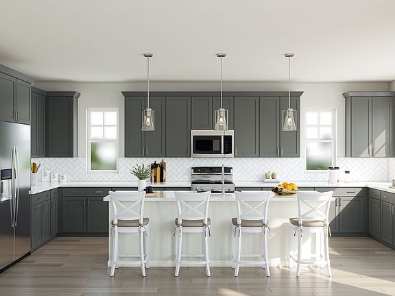 A modern, well-designed kitchen with gray cabinets, white countertops, and pendant lighting over a c