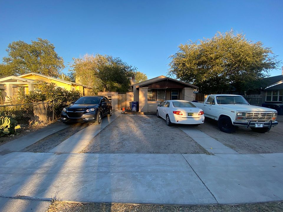 Front of Building, Entry Gate at left between Grey SuU and White Sedan