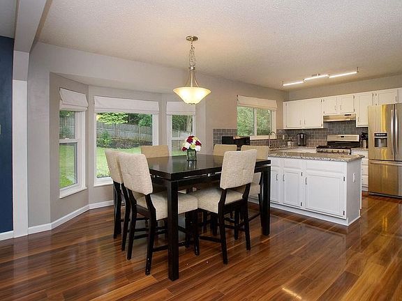 Breakfast room with bay window and laminate flooring opens into kitchen.