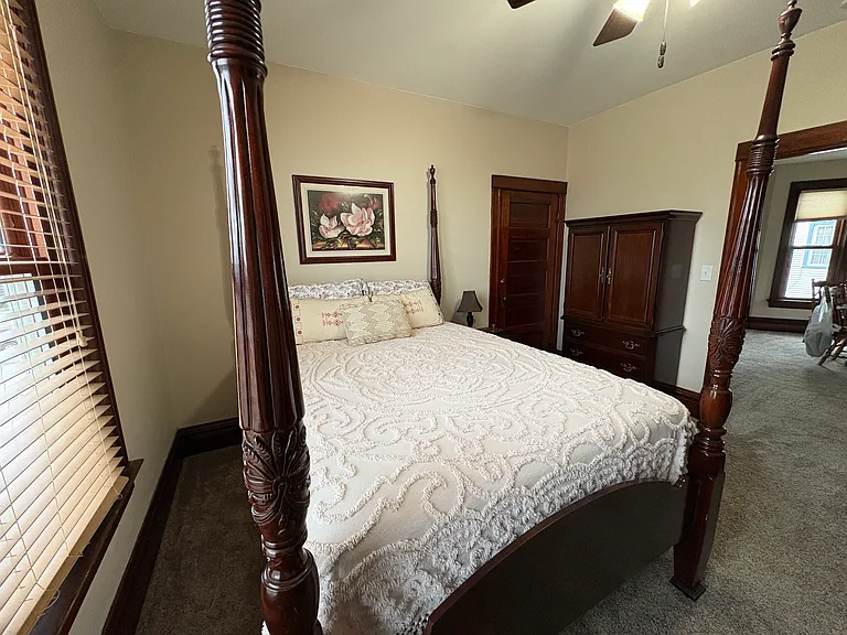 Primary bedroom is complete with four-poster bed, armoir and TV dresser.