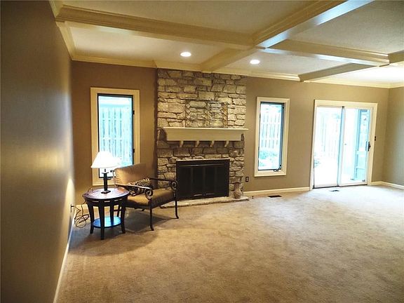 The Great room features a wonderful coffered ceiling, stone fireplace, new carpet, and views to the back intimate courtyard.