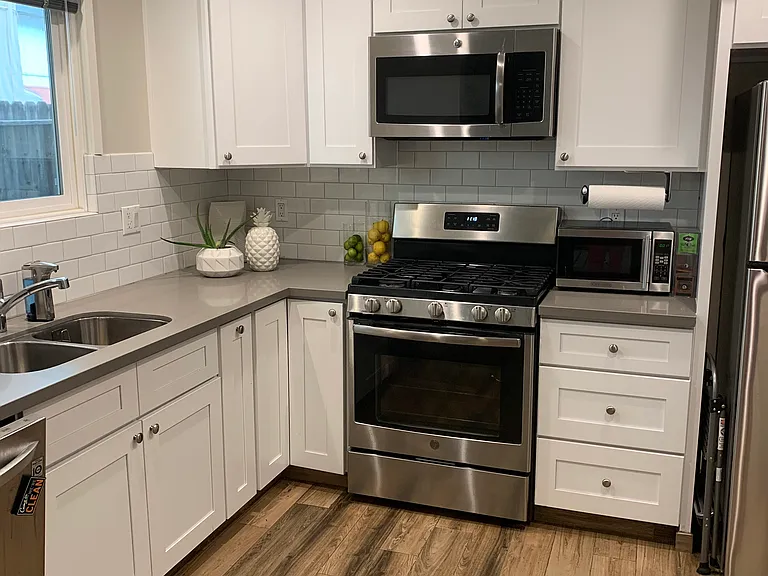 Unit 11 gourmet kitchen includes stainless steel refrigerator, gas stove, dishwasher & microwave. Corner & spice special cabinets. Gray quartz countertop. View of your private patio too!