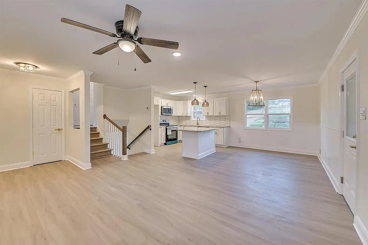 Open-concept main level with spacious living area flowing into an eat-in kitchen with island seating and ample cabinetry. - Sprucewood Dr
