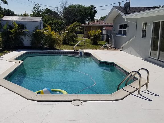 Large pool in fenced yard with tool or she shed