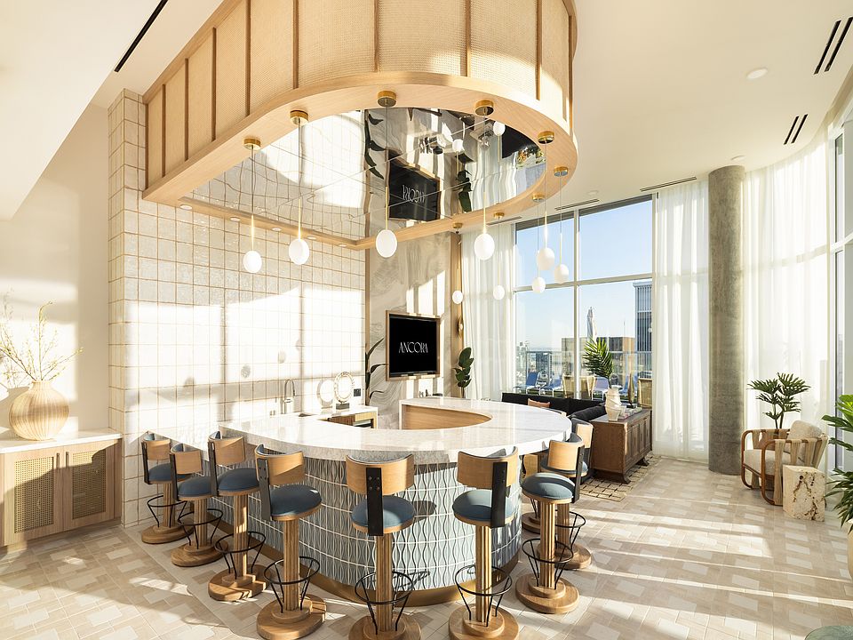 Luxurious modern kitchen with a unique curved island, elegant bar stools, and expansive floor-to-ceiling windows offering stunning city views.