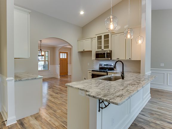 Vaulted kitchen w/granite, stainless appliances, 42" cabinets, & subway tile backsplash.