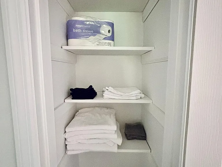 Built-in linen closet with multiple shelves for storing towels, toiletries, and household essentials.