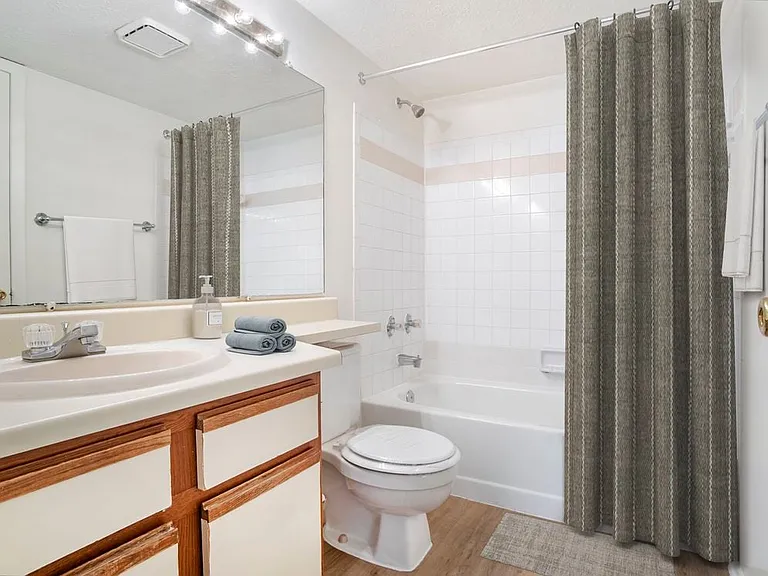 Renovated Meadows I bath with white laminate countertops, cream cabinetry with wood trim, and hard surface flooring