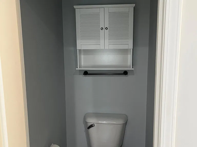 Private water closet with built-in wall storage.