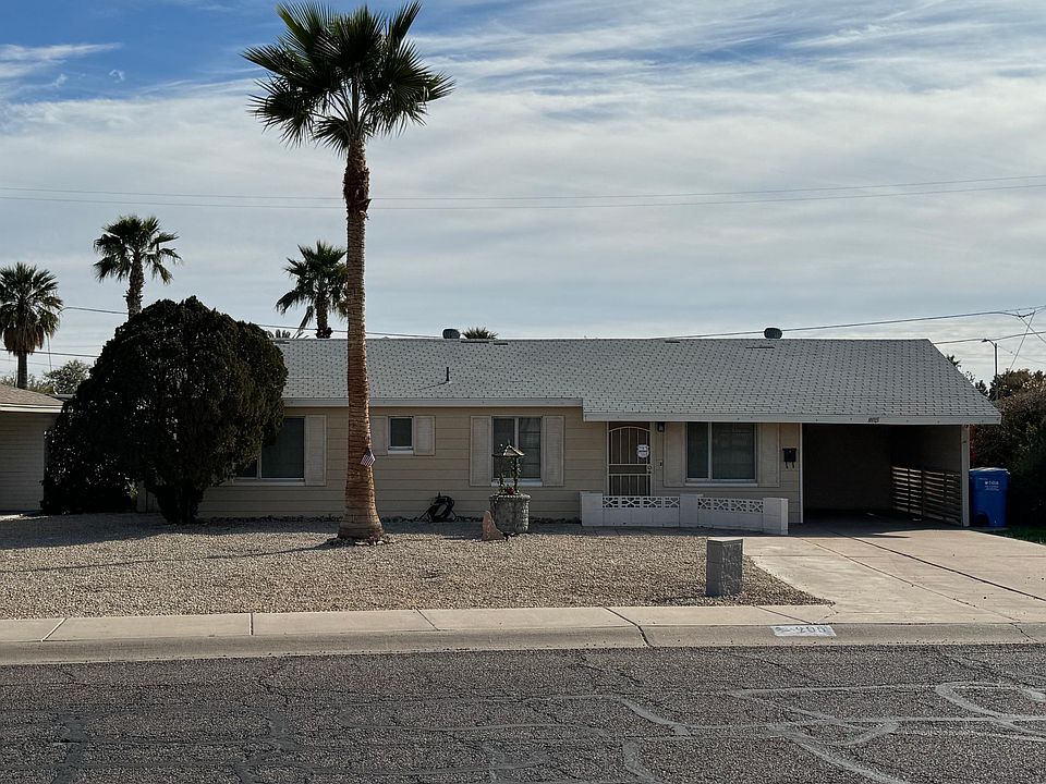 Street view of home and front yard, large driveway and one car carport.