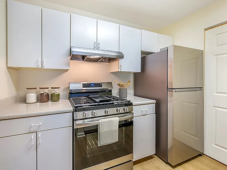 Classic Package II kitchen with stainless steel appliances, white laminate countertops, white cabinetry, and hard surface flooring