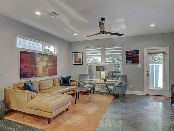 Living room is open and bright with recessed lighting, transom windows, and windows across the back looking into the fenced back yard.