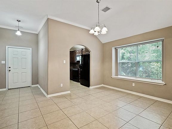 Dining room offering a gorgeous neutral color, crown molding, tile flooring, charming chandler and tons of natural light!