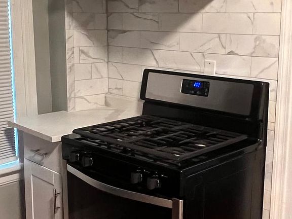Additional new Shaker Cabinetry on the other side of the kitchen quartz countertop, new stainless steel gas stove.