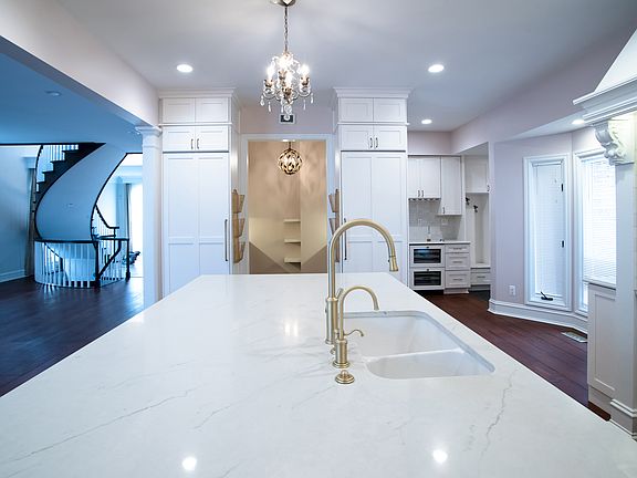 Expansive stone-covered island with custom double sink, filtered water tap, and built-in Miele dishwasher and microwave. Seating for four at the island, with the bay window giving a nice space for a high-top table at your breakfast nook