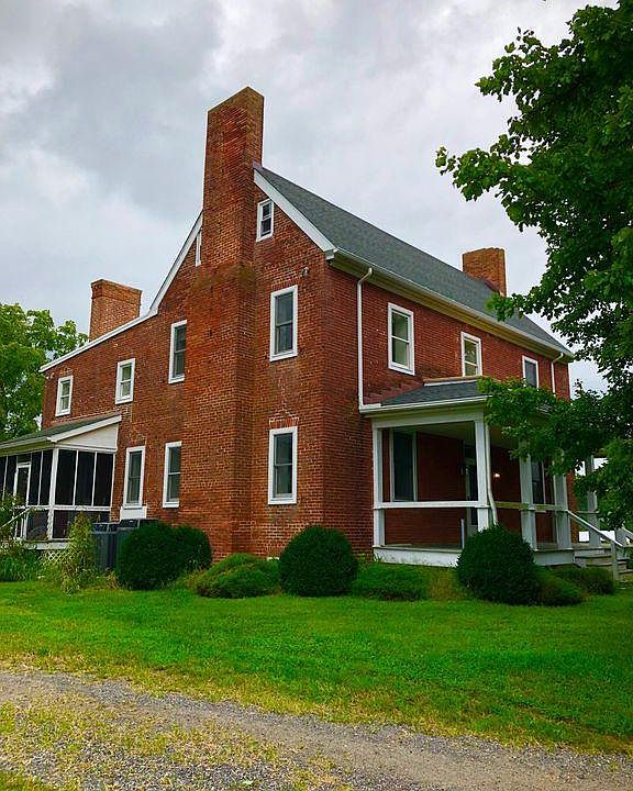Farmhouse with front porch and main entrance, side screened porch and kitchen entrance.
