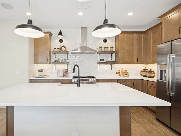 Kitchen with floating shelves and stainless steel hood