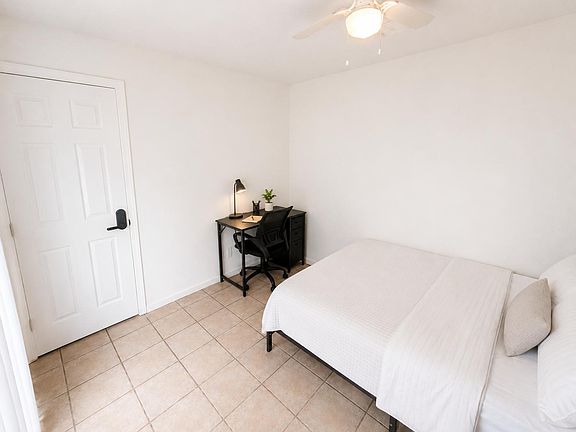 Furnished bedroom with tile flooring, ceiling fan, and a dedicated desk/workstationideal for studying or remote work.