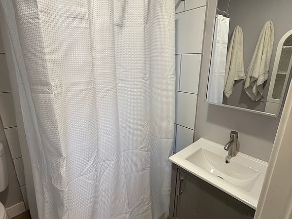 Stylish bathroom with shower, fluffy towels, and good storage for all your personal care items.