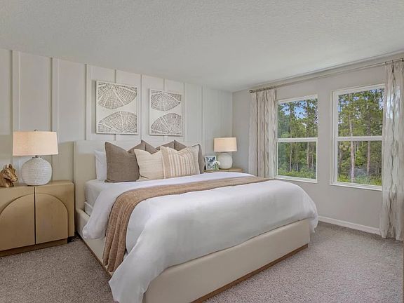 Spacious primary bedroom featuring plush carpet, a ceiling fan, and large windows that provide abundant natural light.