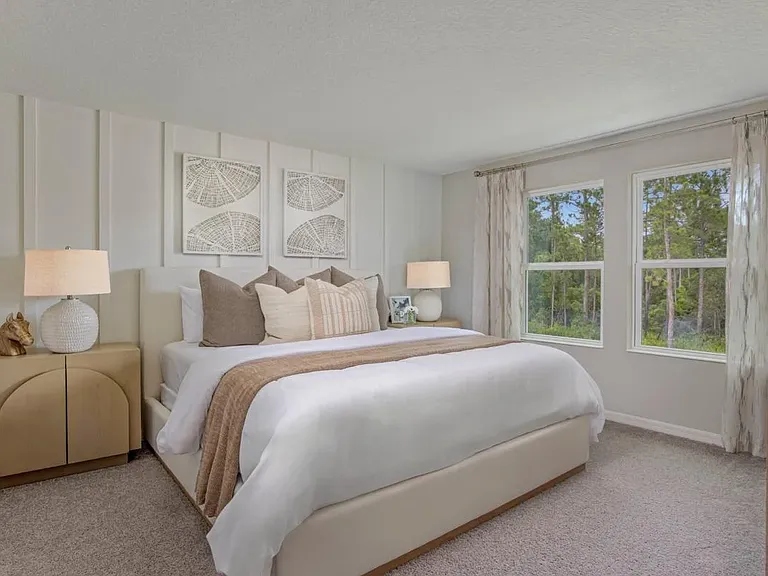 Spacious primary bedroom featuring plush carpet, a ceiling fan, and large windows that provide abundant natural light.